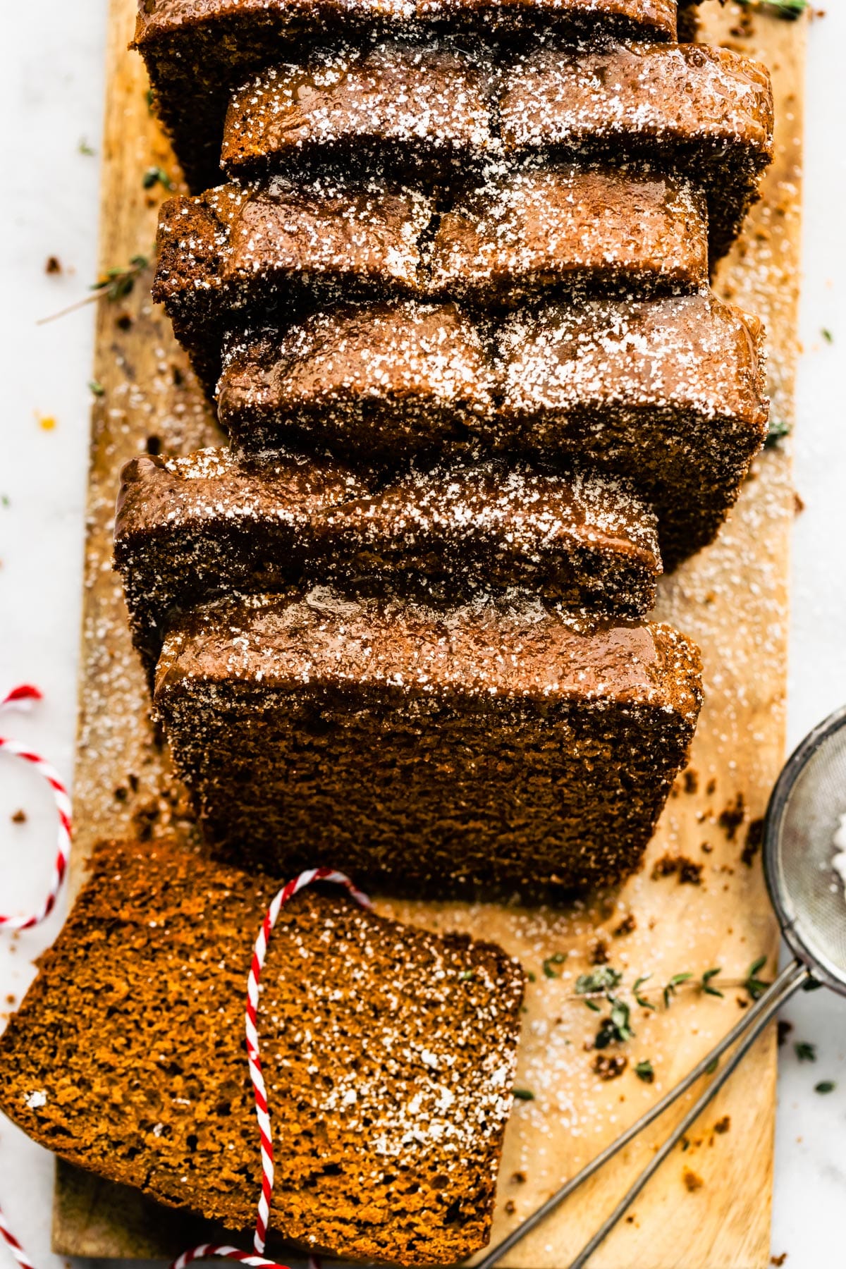 Sliced gingerbread on a wooden cutting board sprinkled with powdered sugar.