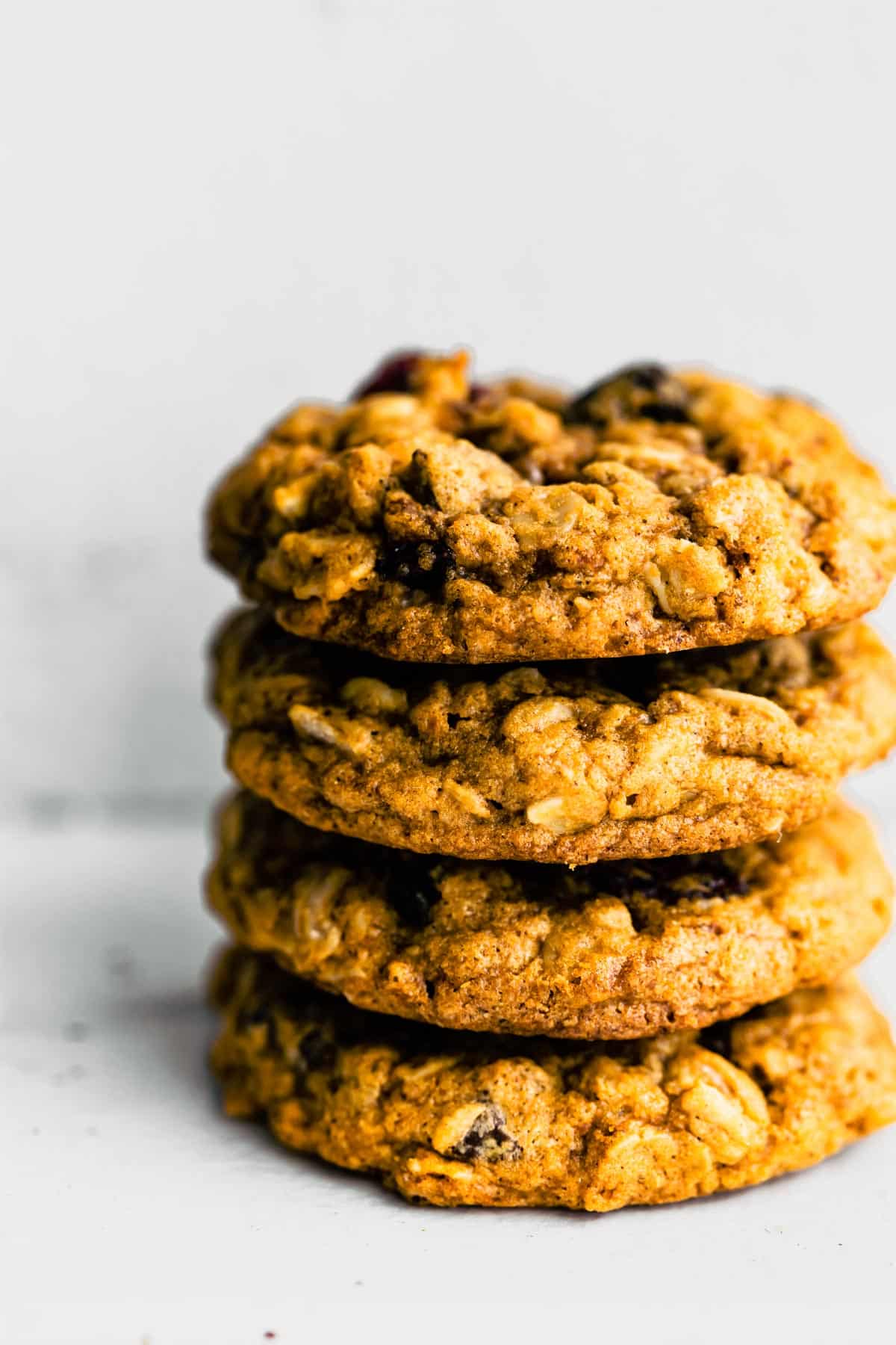 A stack of four gluten free oatmeal cookies with chocolate chips on a white countertop.