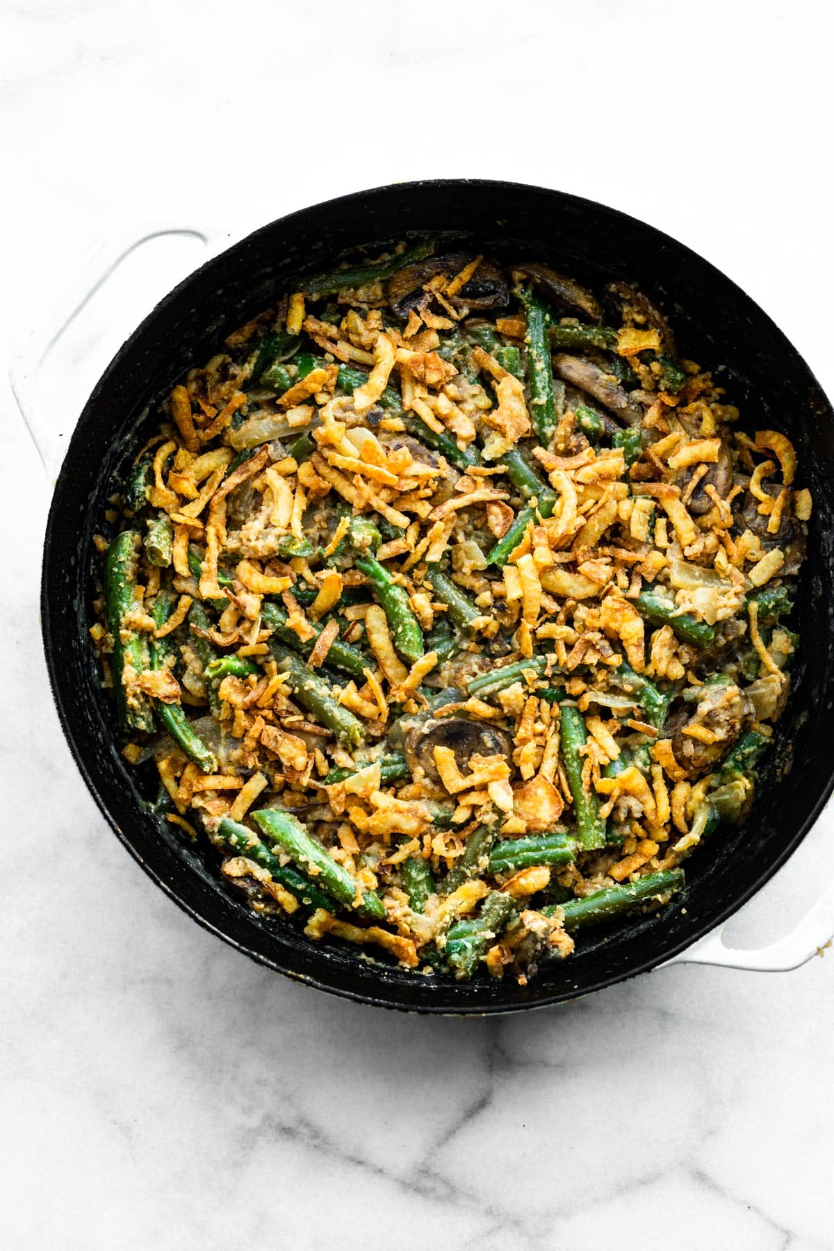 A pan of vegan green bean casserole topped with crispy fried onions.