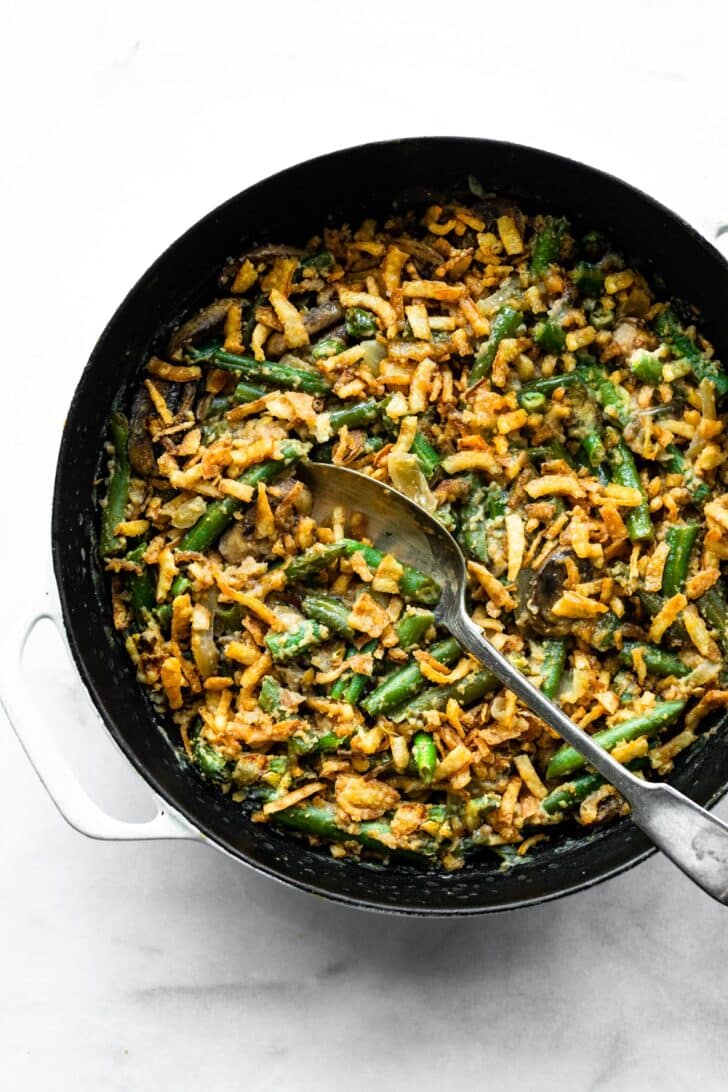 Overhead photo of a spoon in a skillet of vegan green bean casserole.