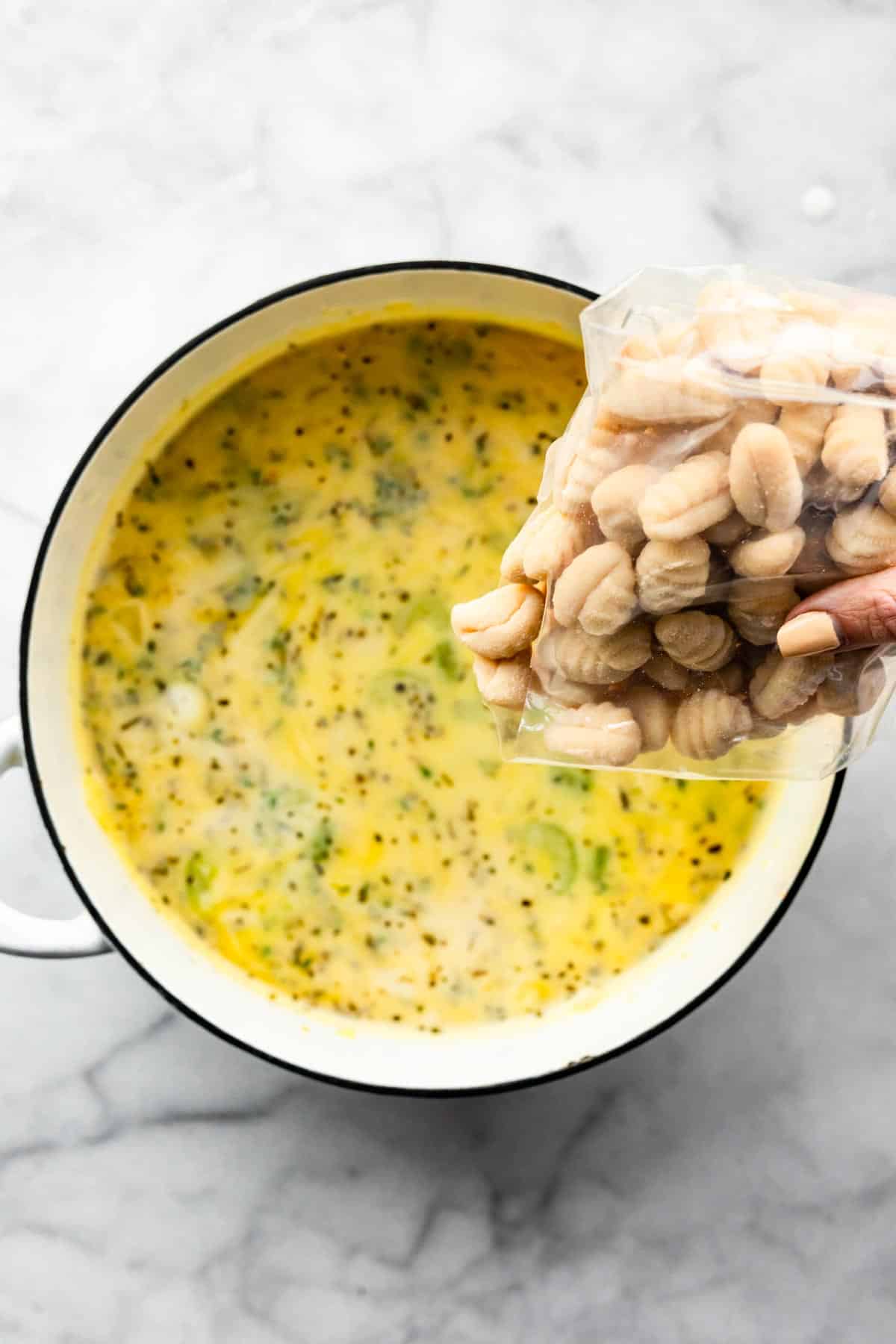 Gluten free gnocchi poured into a pot of creamy chicken and gnocchi soup.