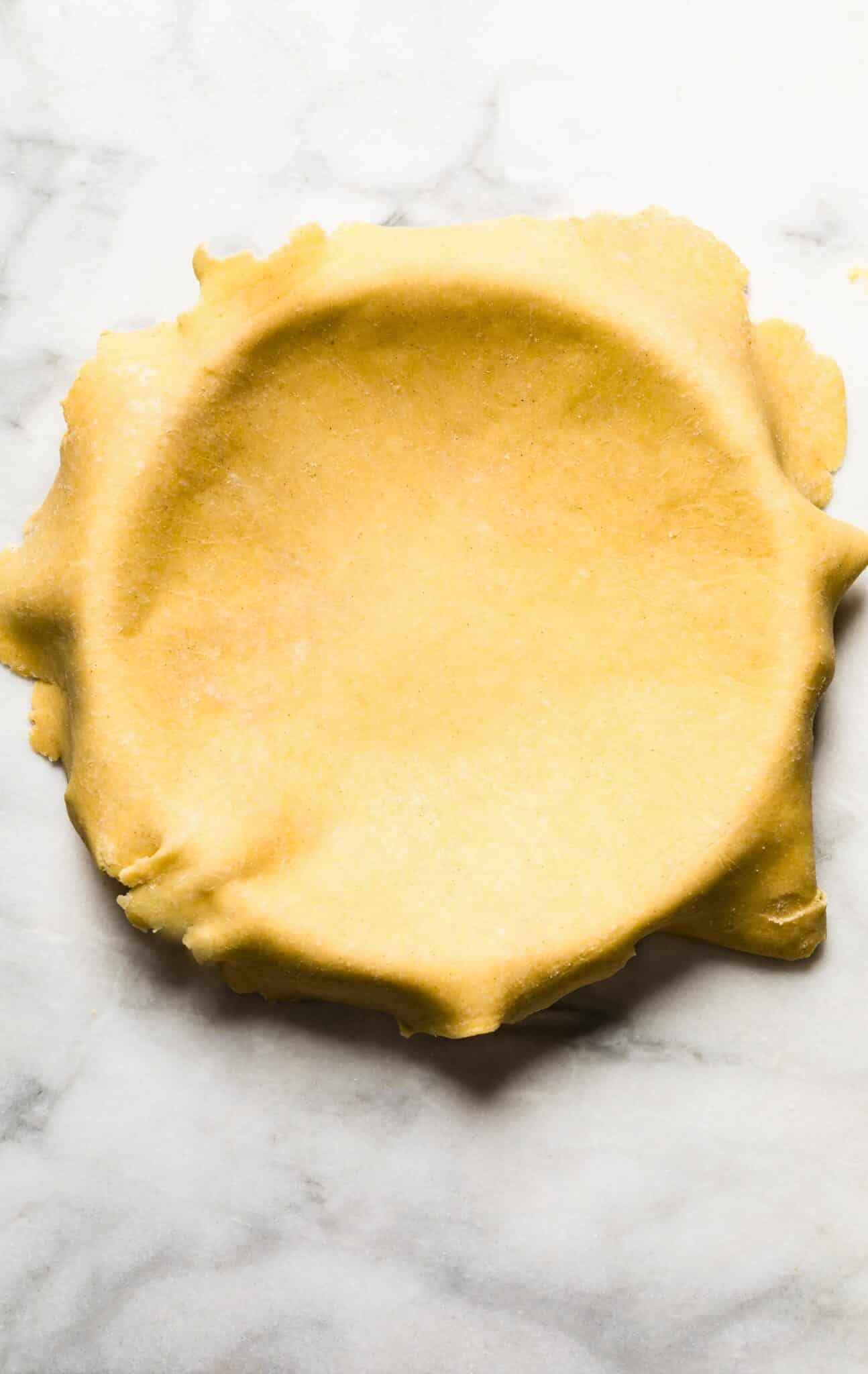 A gluten free pie crust rolled out and laying on a pie tin.