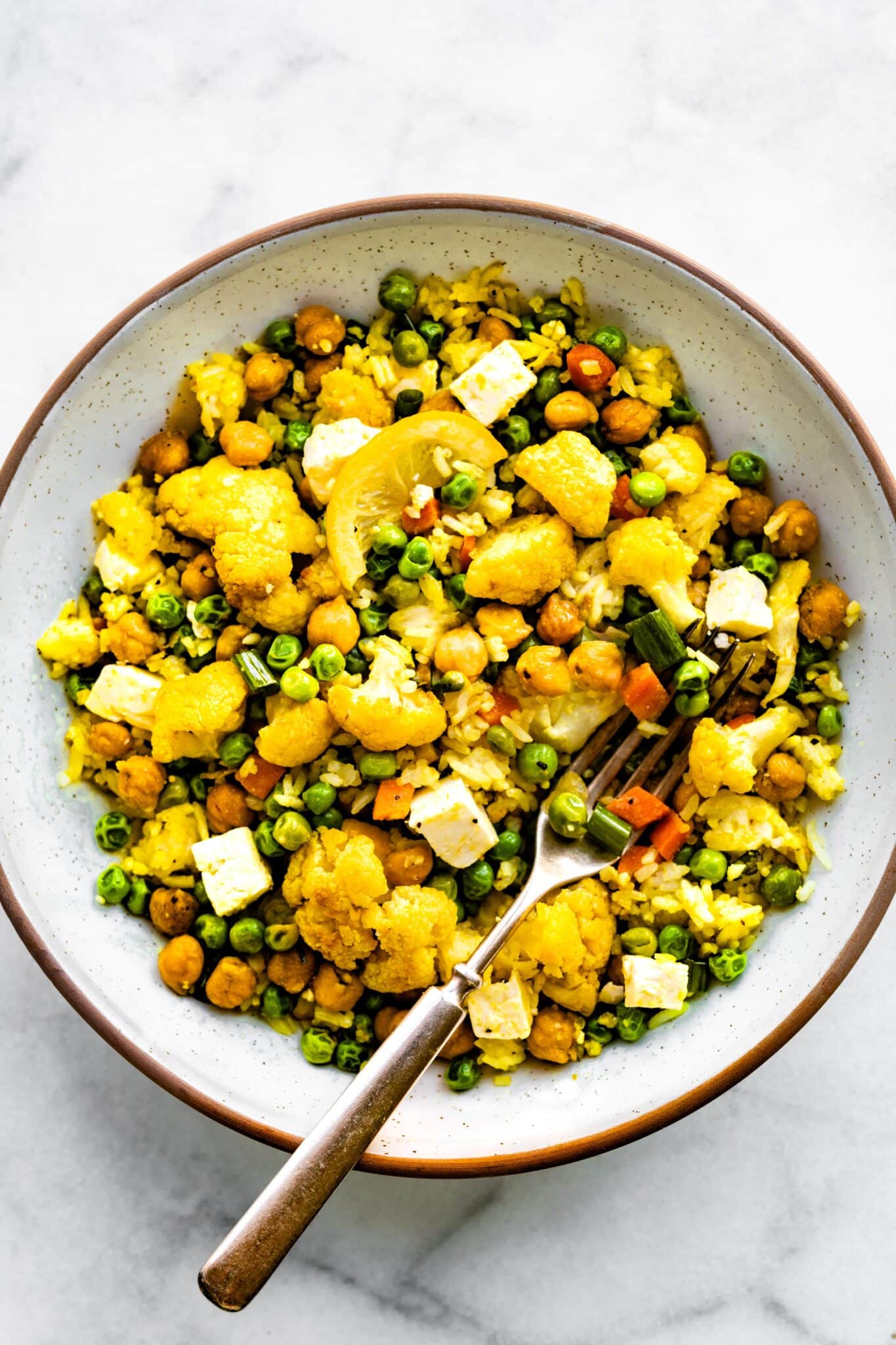 Overhead photo of a bowl of curried cauliflower bake with a fork on top.