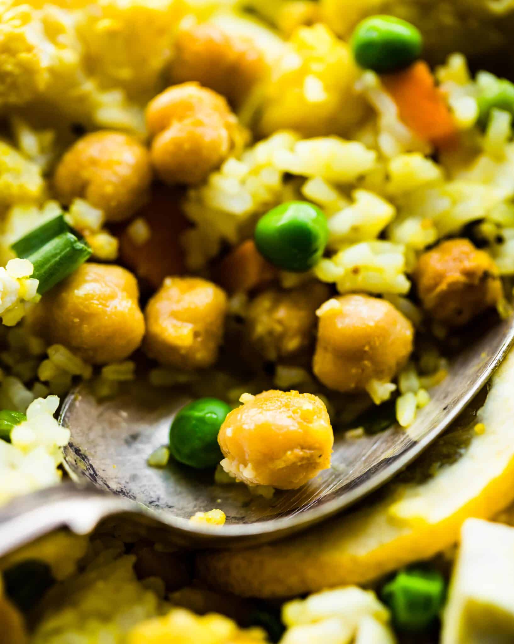 Up close photo of vegetarian curried cauliflower bake with chickpeas on a spoon.