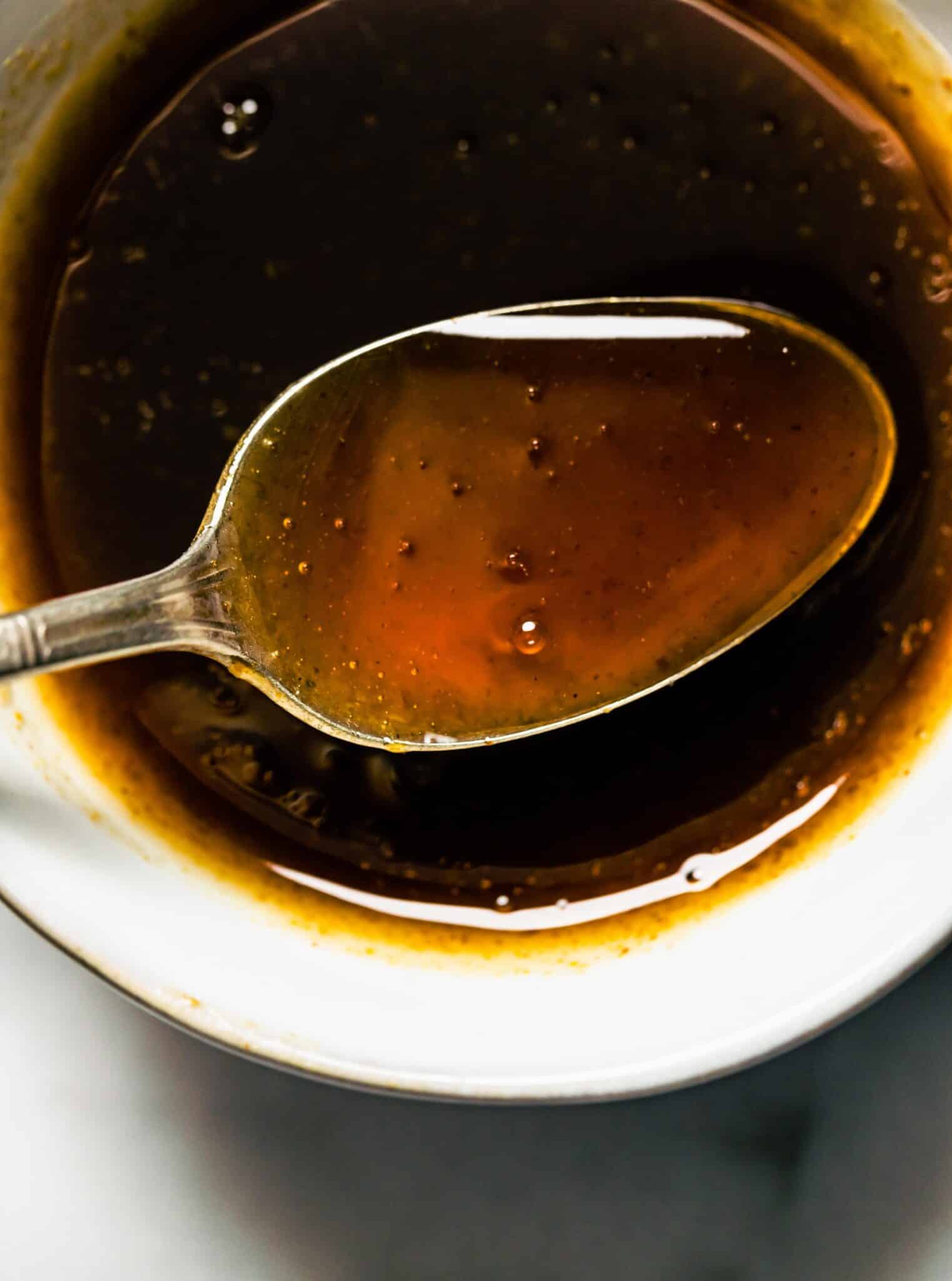 Up close photo of a homemade maple bourbon glaze recipe on a spoon.