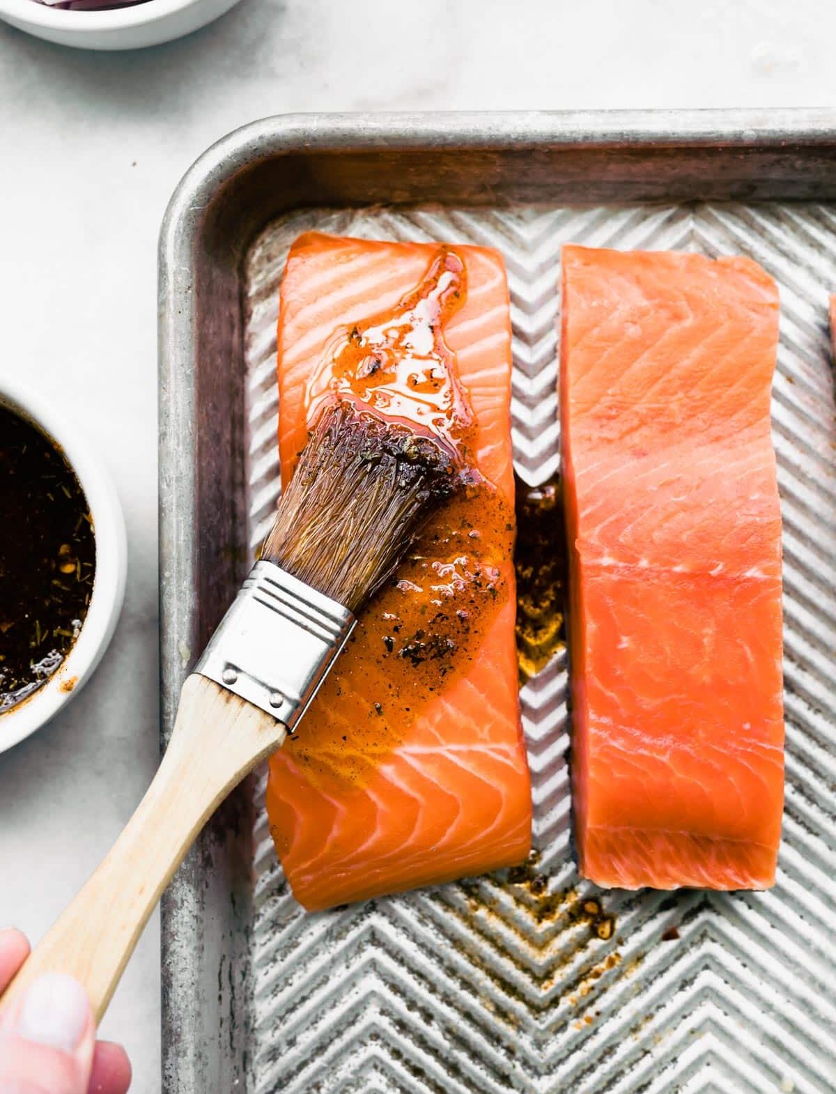 Overhead photo of a maple bourbon glaze being brushed on a salmon filet.