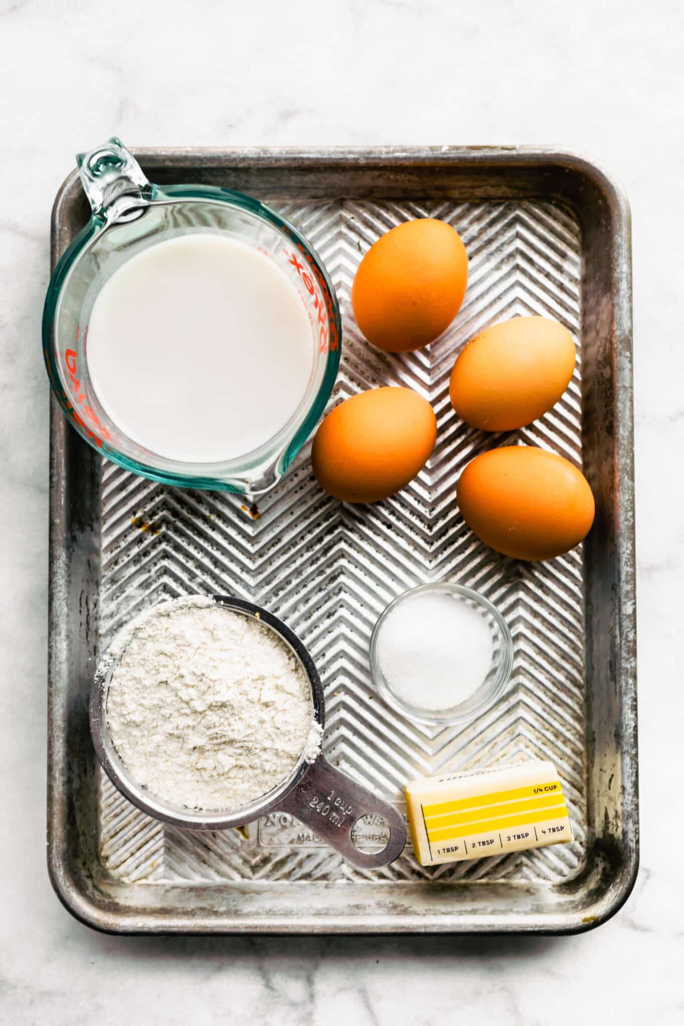 Coconut milk, eggs, butter and gluten free flour for Swedish Pancakes on a baking sheet.