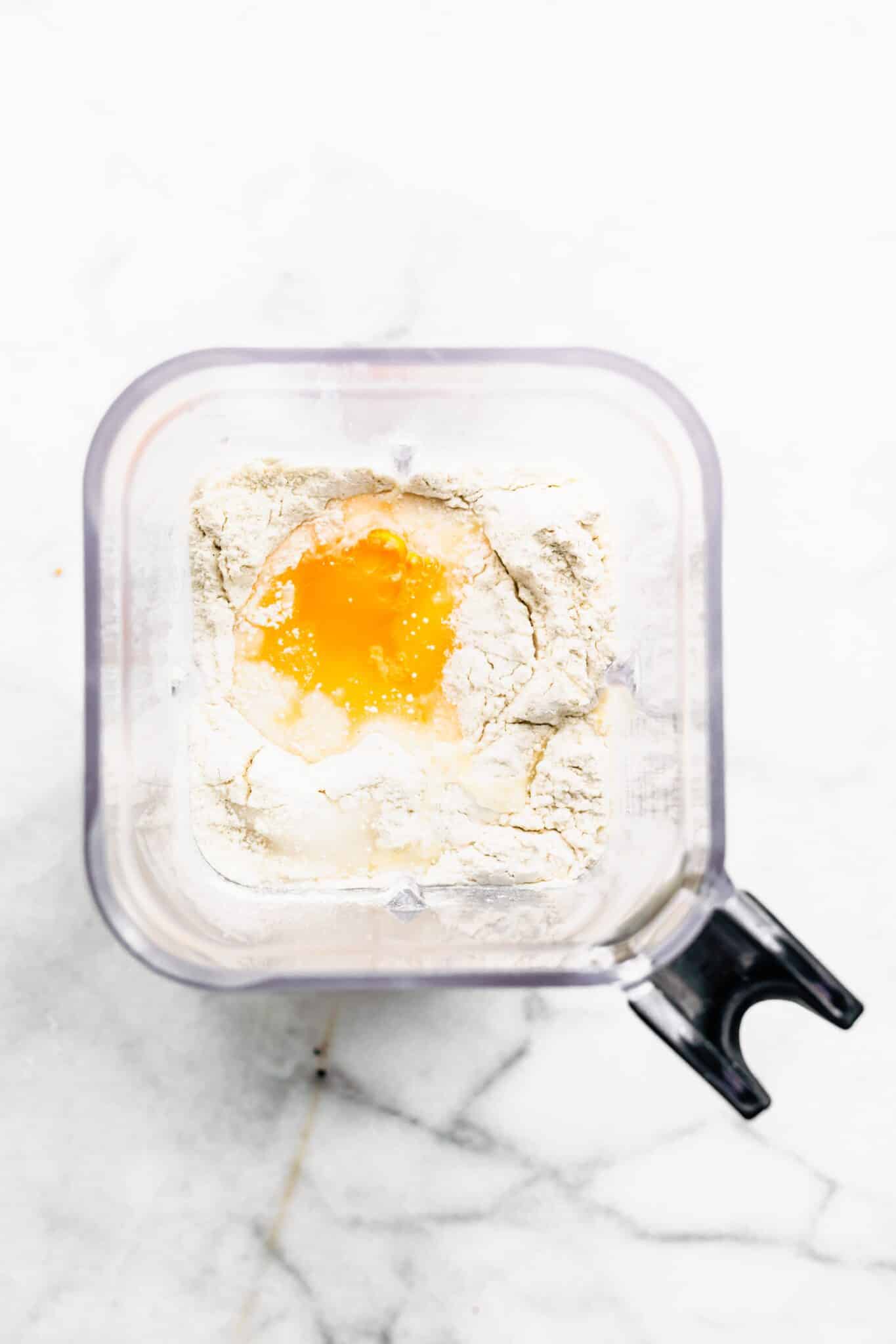 Overhead photo of a blender filled with gluten free flour, eggs and milk.