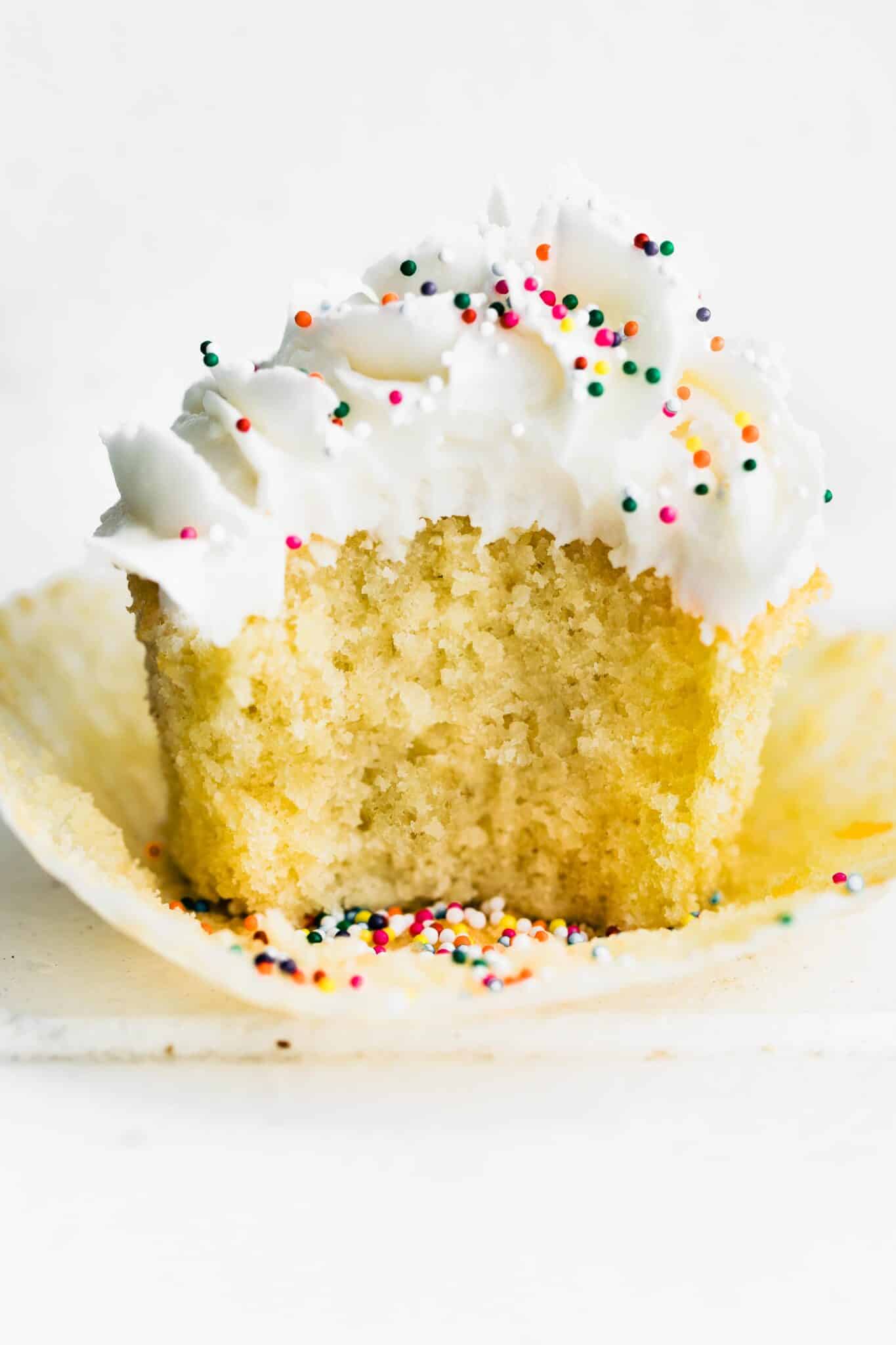 Up close photo of gluten free vanilla cupcakes with a bite taken out of it.