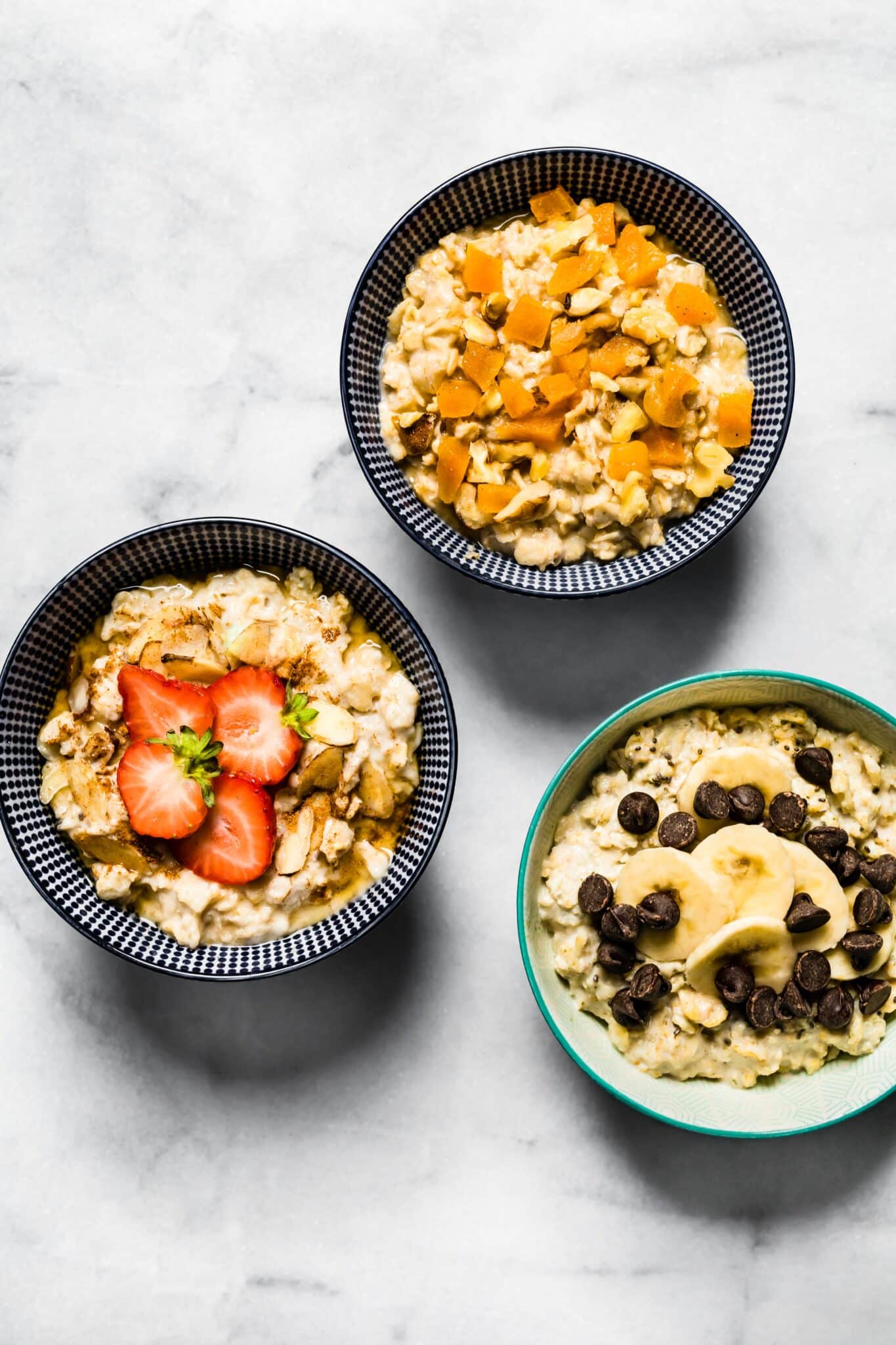Three bowls of gluten free high protein oatmeal with fresh fruit or chocolate chips.