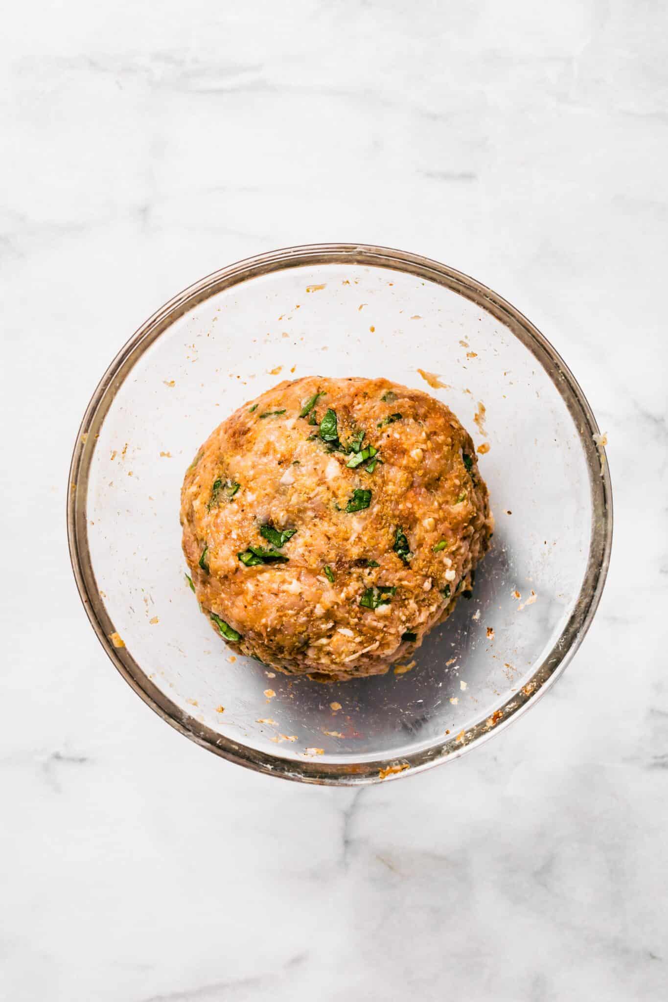 Overhead photo of gluten free chicken meatball mixture in a glass bowl.