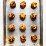 Overhead photo of twelve cooked gluten free chicken meatballs on a sheet pan.