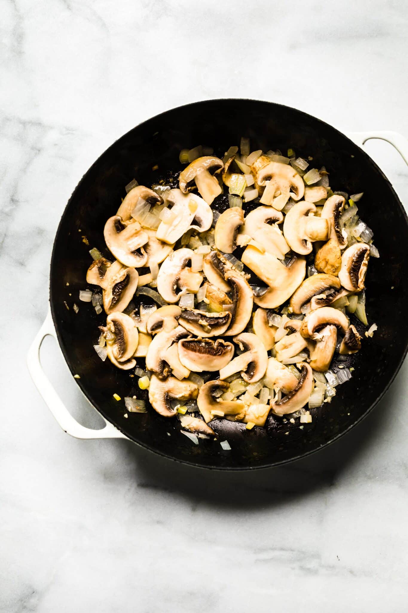 Overhead photo of sauteed onions and mushrooms in a cast iron pan.