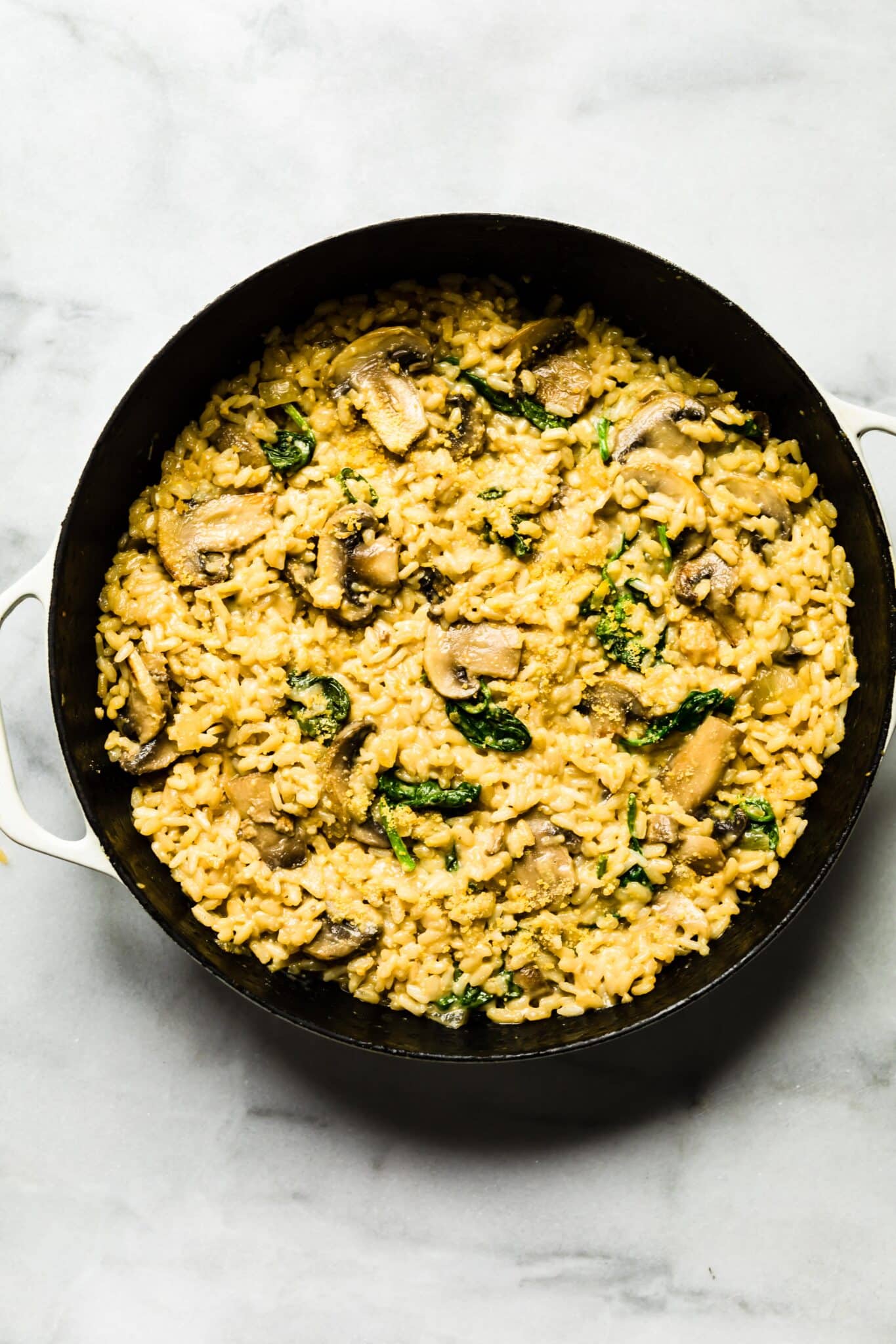 Creamy mushroom risotto in a cast iron pan with spinach and cheese