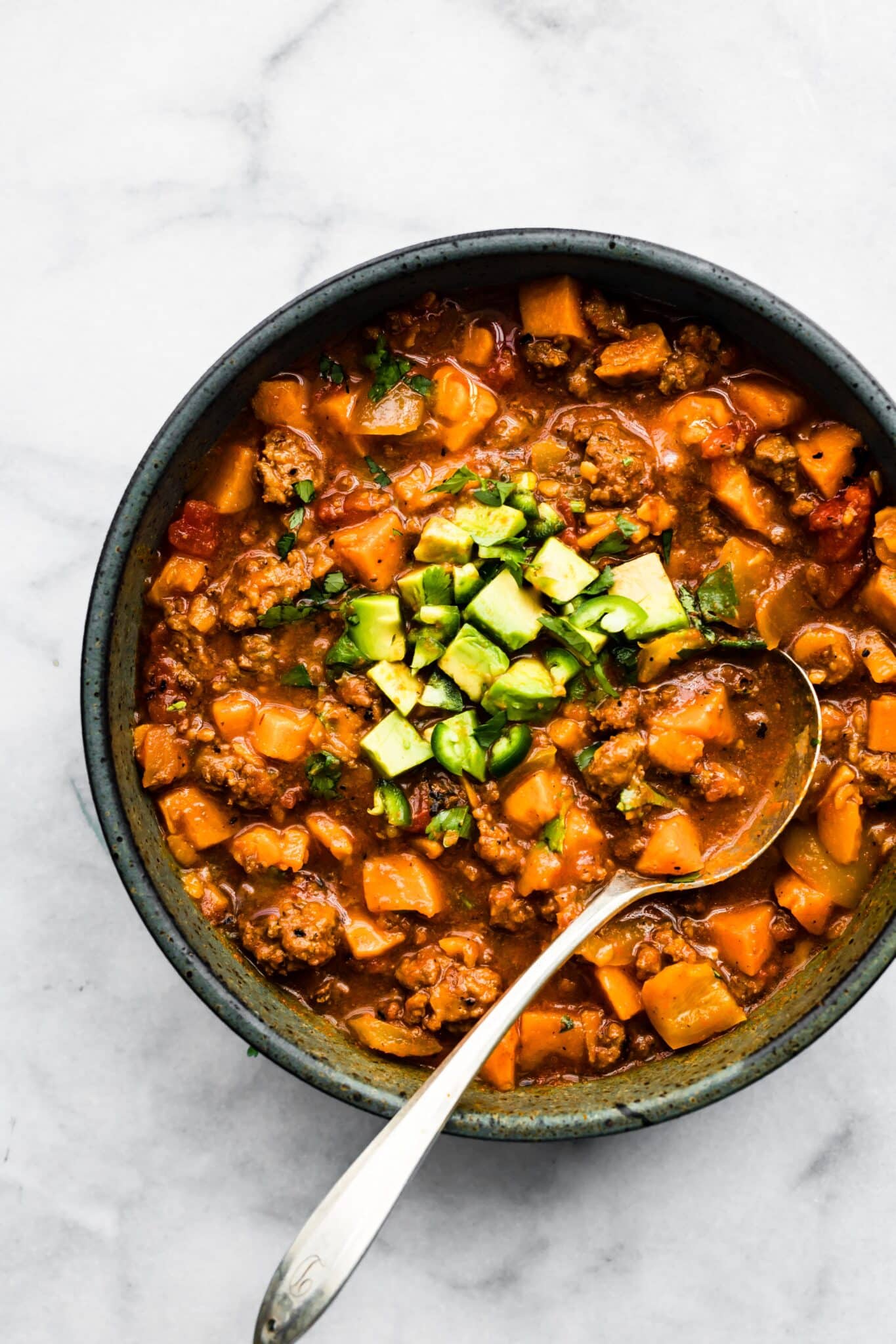 Overhead photo of Chipotle Sweet Potato Chili in a bowl topped with diced avocado.