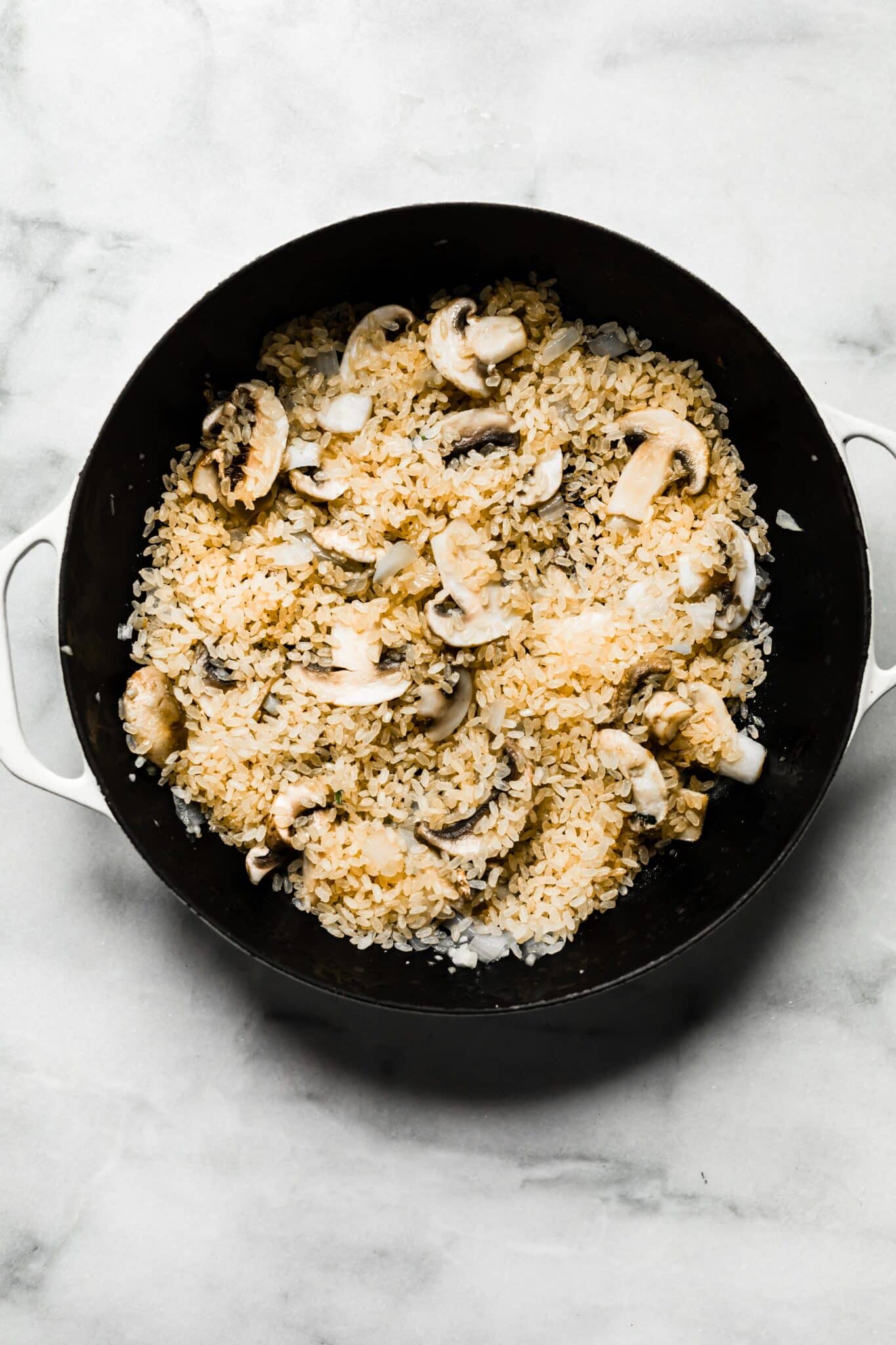 Overhead photo of rice and mushrooms in a cast iron pan.
