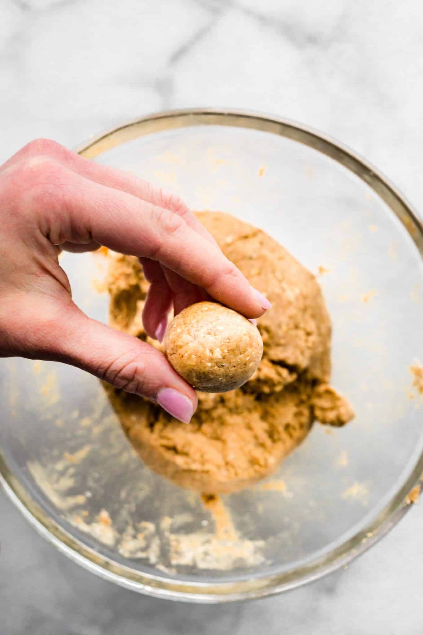 A woman's fingers holding a cinnamon protein breakfast ball.