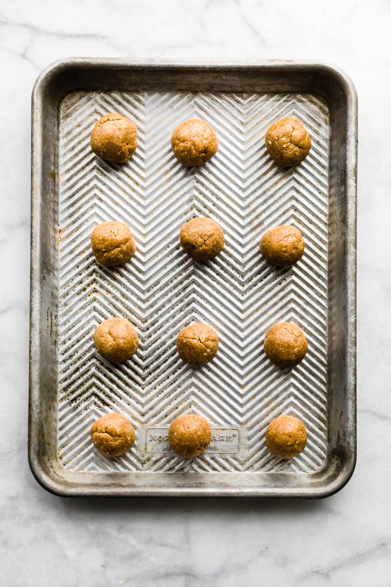 Twelve cinnamon breakfast balls with protein on a metal baking sheet .