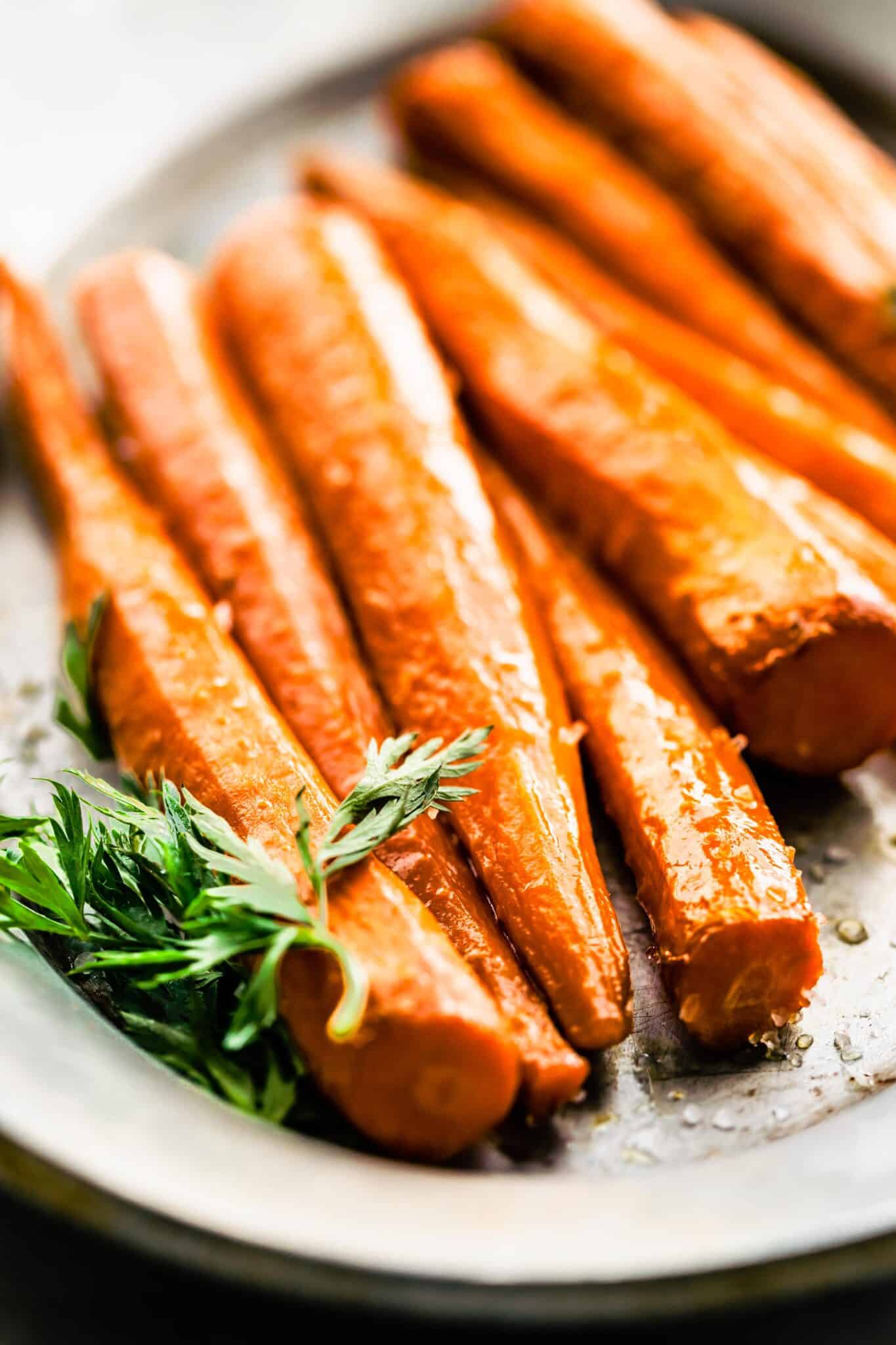 Up close photo of maple glazed carrots on a metal platter.