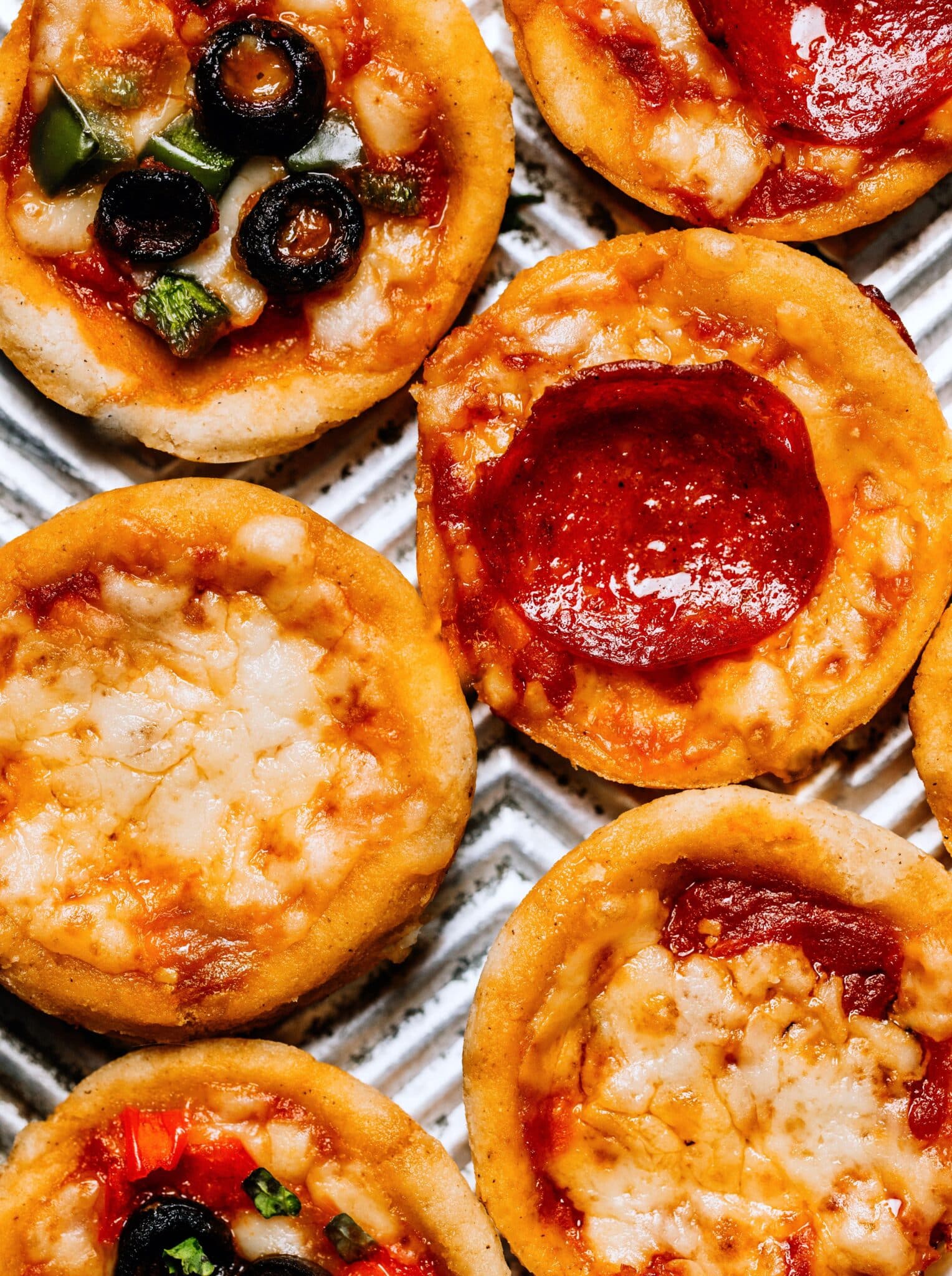 Overhead photo of pizza muffins tipped with pepperoni, olives or cheese.