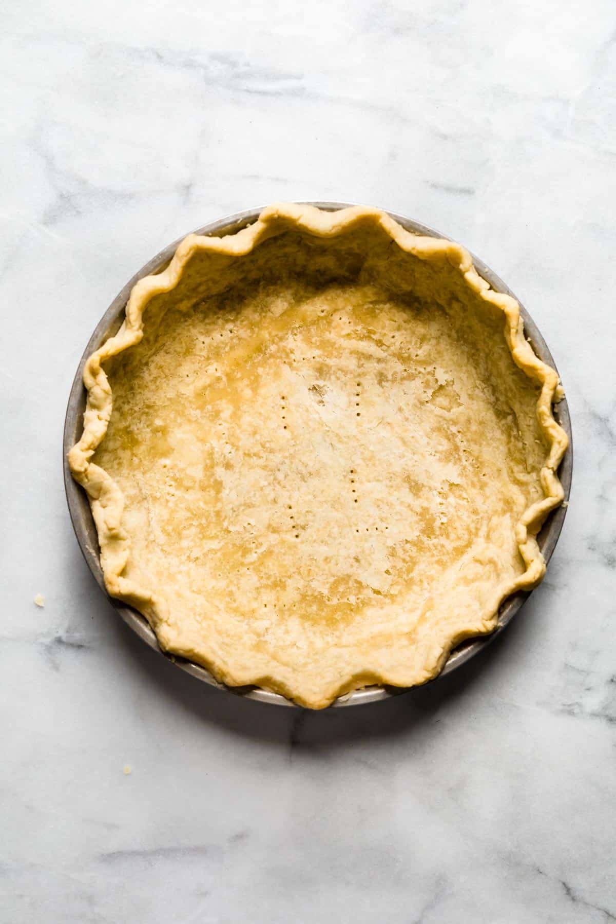 A docked gluten free pie crust that is par baked.