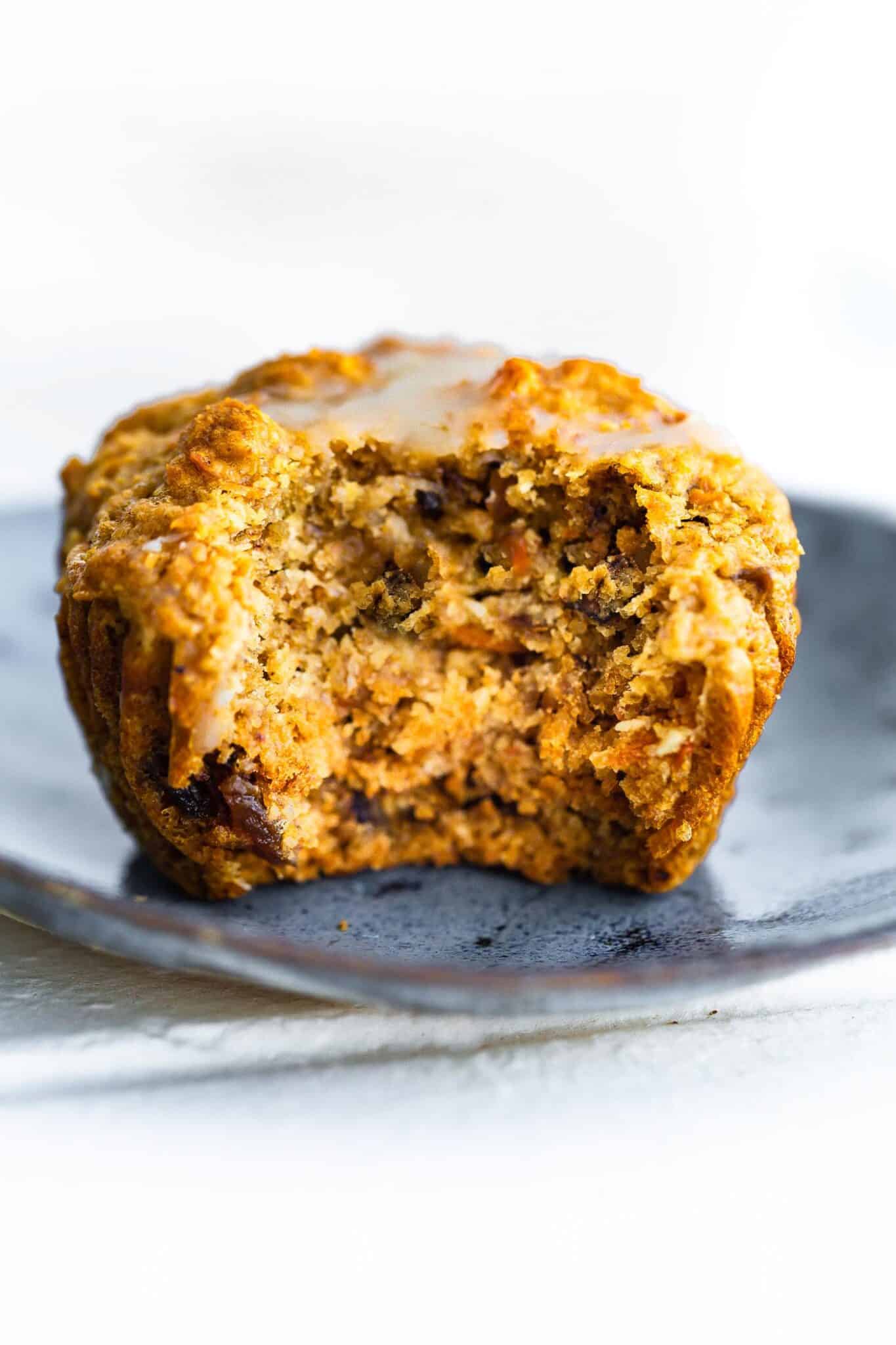 Up close photo of a gluten free carrot cake muffin with a bite taken out.