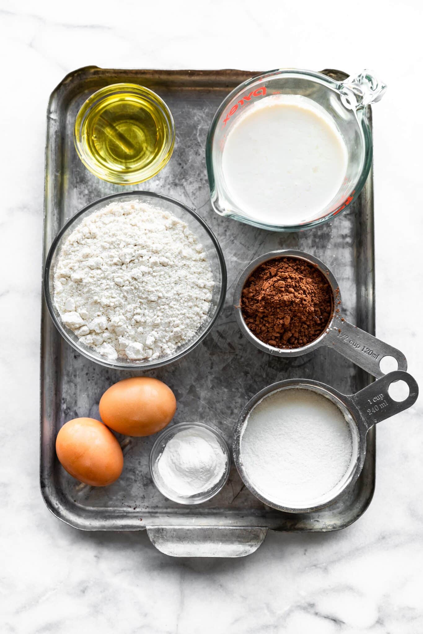 Overhead photo of ingredients in bowls on a baking sheet for gluten free chocolate cupcakes.