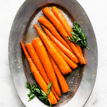 Overhead photo of saucy maple glazed carrots sprinkled with flaked sea salt.