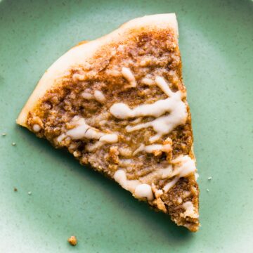 Overhead photo of a slice of cinnamon dessert pizza on a green plate.