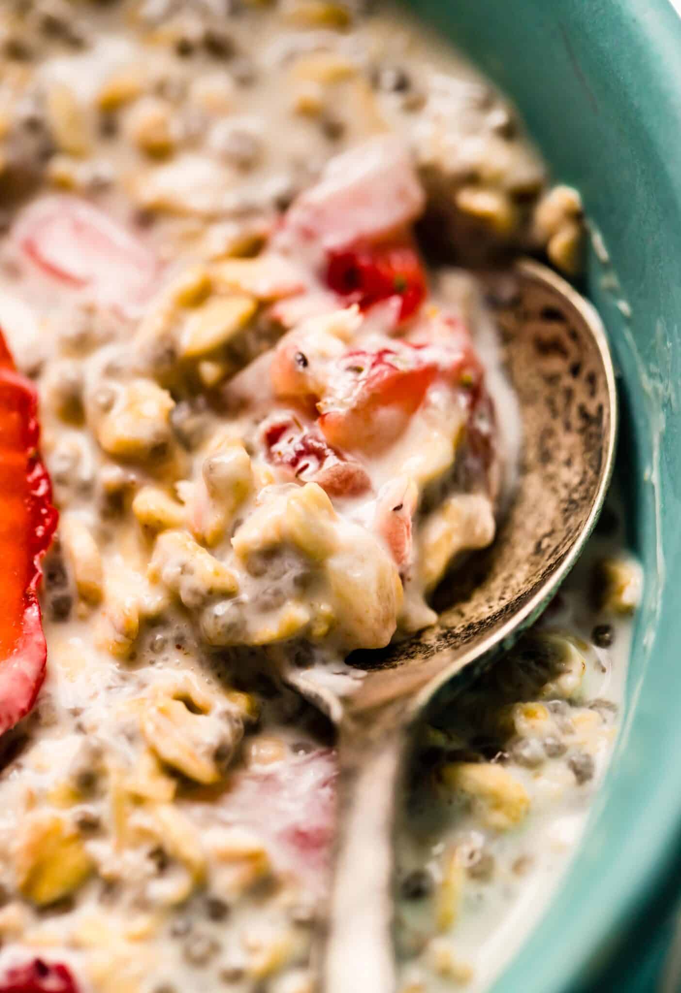Up close photo of a spoon in strawberry overnight oats with chia seeds.