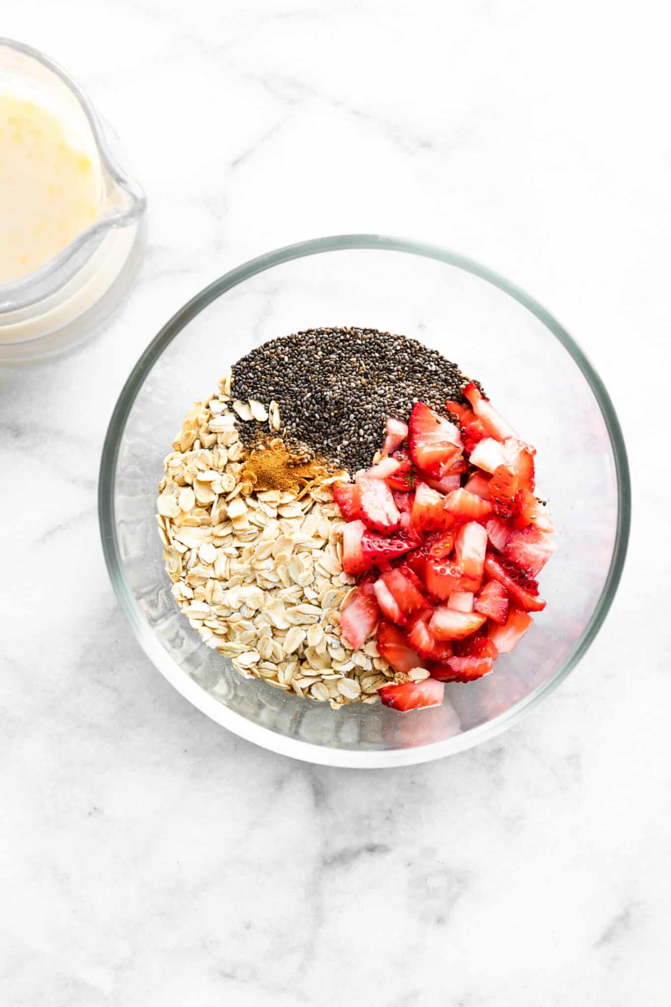 Overhead photo of chia seeds, rolled oats, strawberries and cinnamon in a bowl.