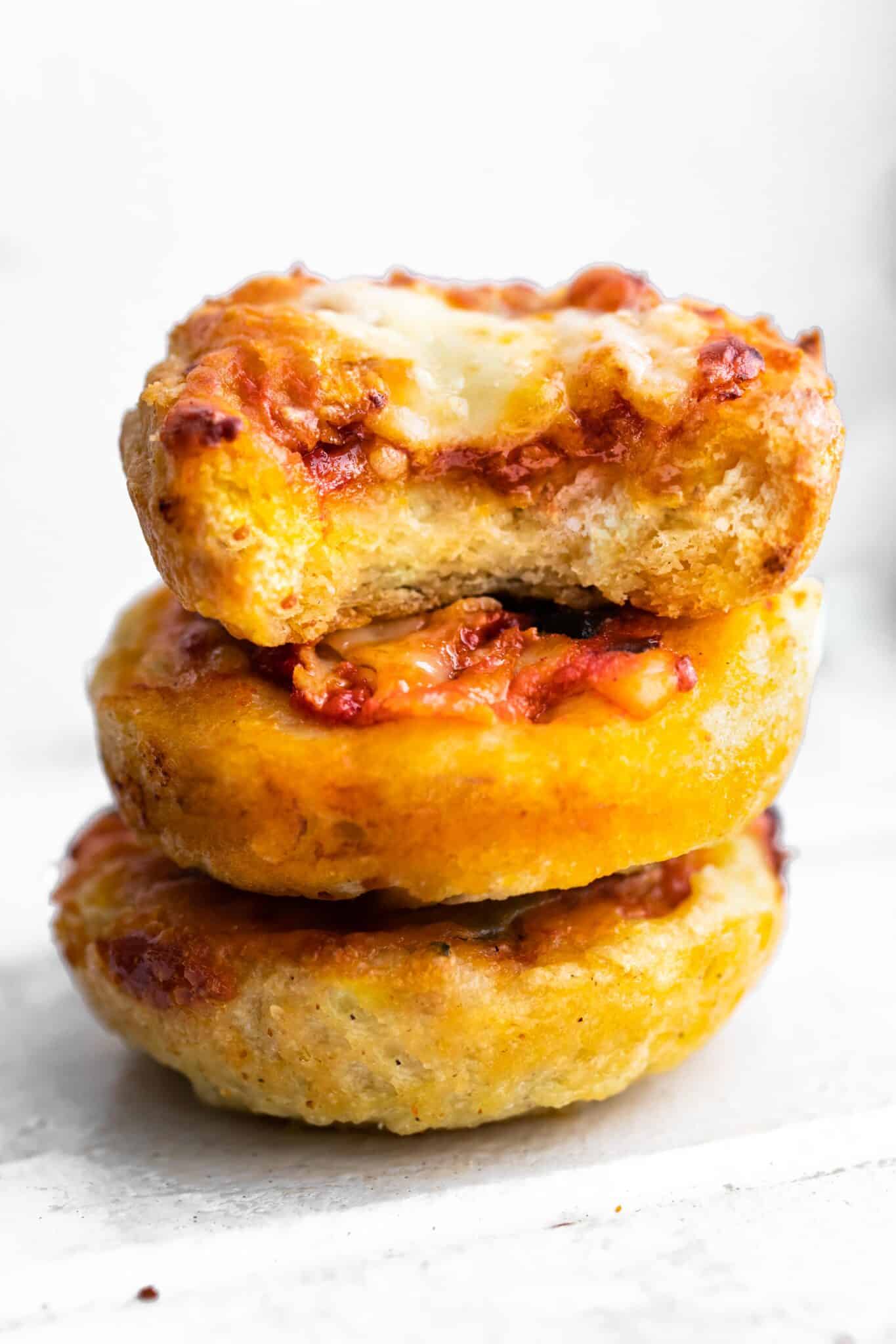 A stack of three pizza muffins with a bite taken out of the top muffin.