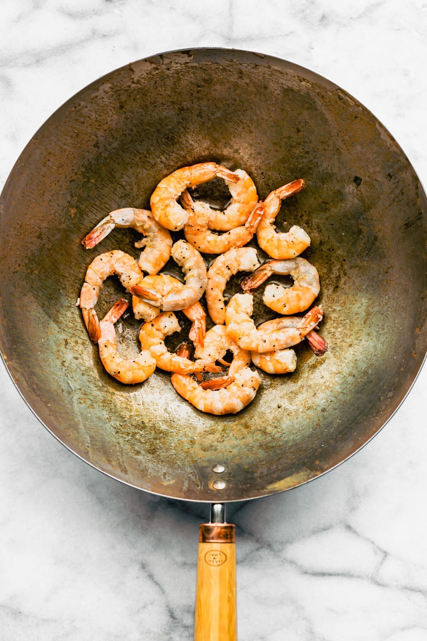 Overhead photo of cooked shrimp in a wok.