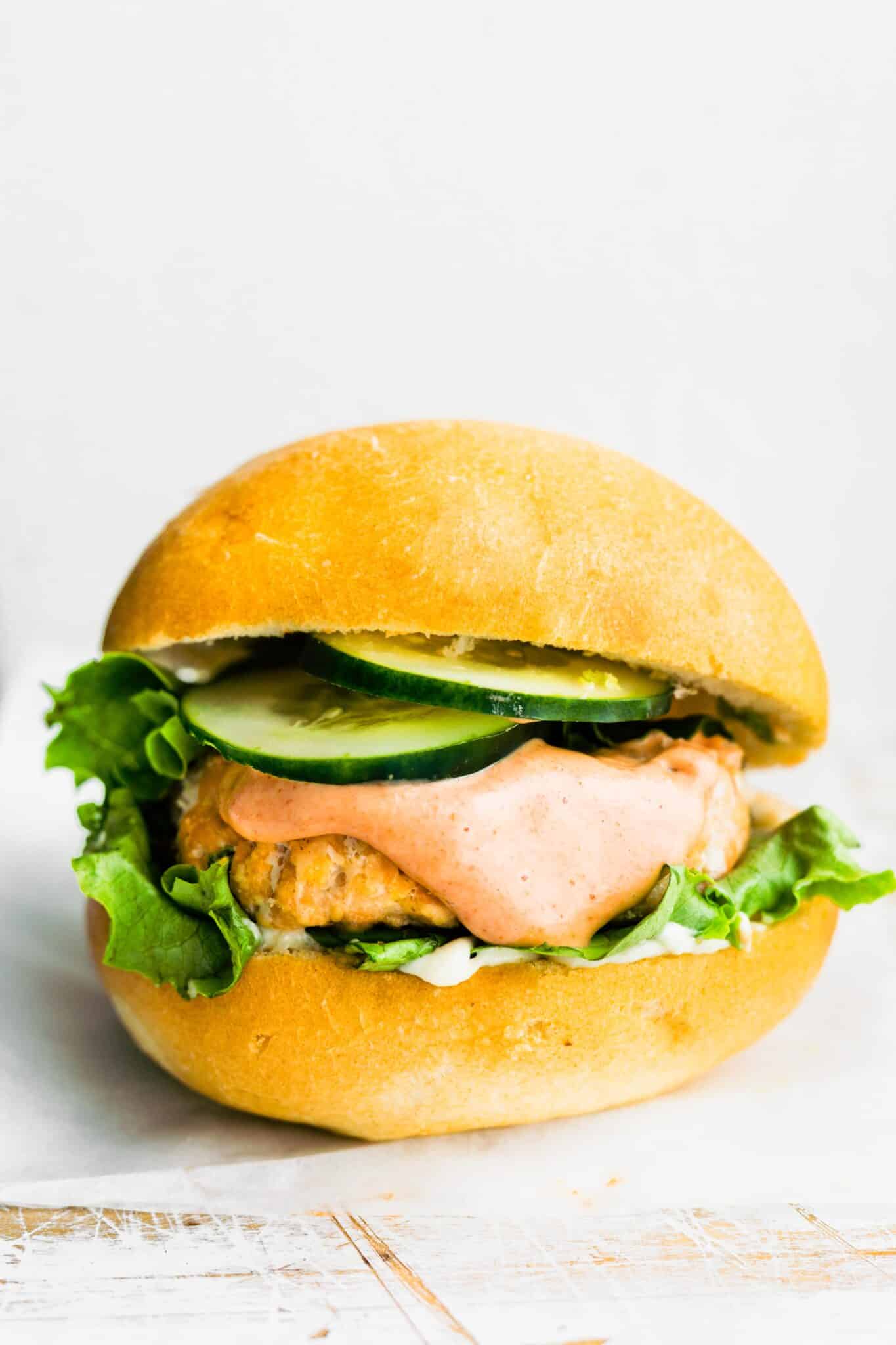 A salmon burger with chipotle mayo, and fresh veggies on a gluten free bun.