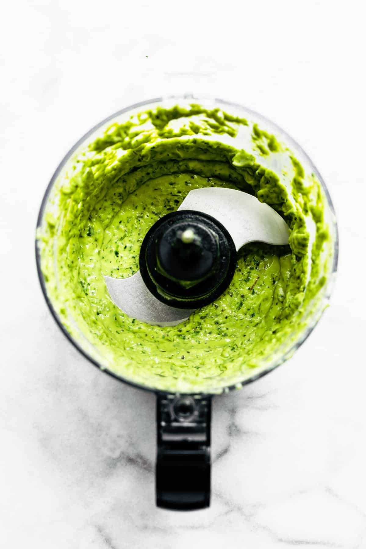 Overhead photo of green goddess dressing in a a food processor.